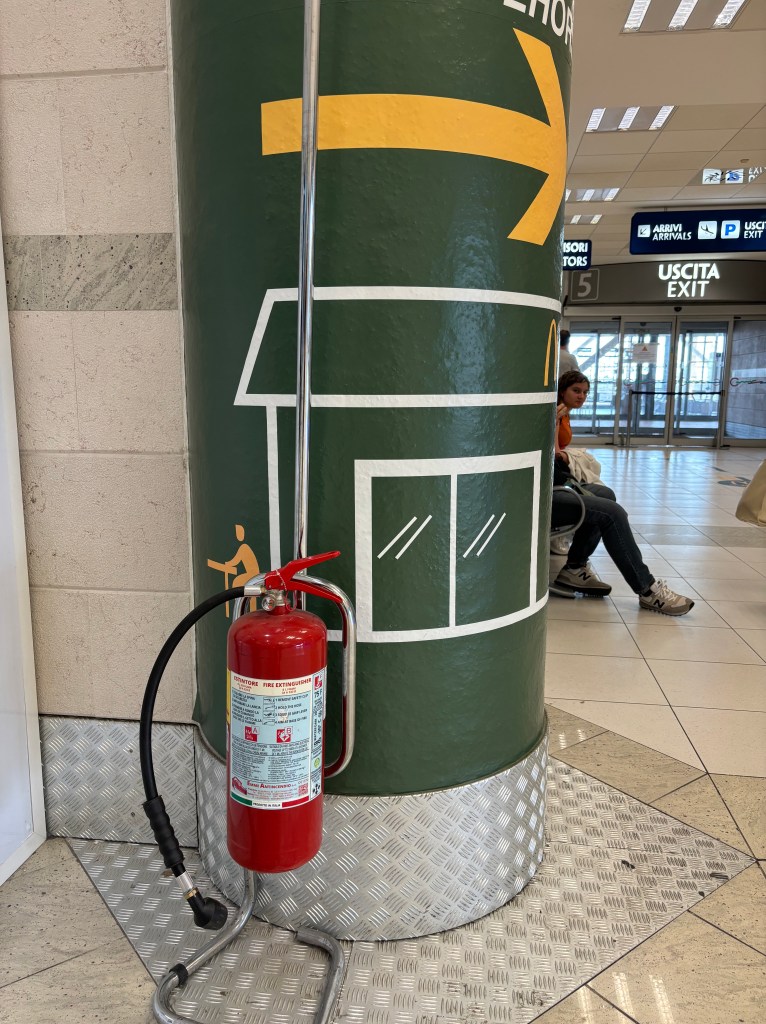 Extinguisher at the airport on a McDonalds' sign pillar